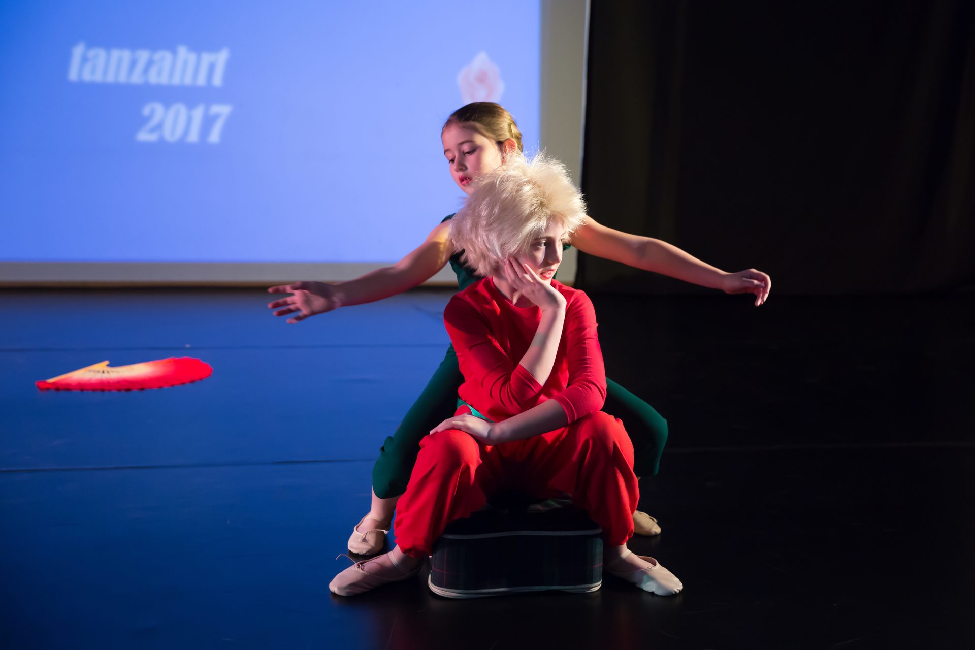 Solistin in rotem Kostüm mit Fächer vor der Projektion „tanzahrt 2017“